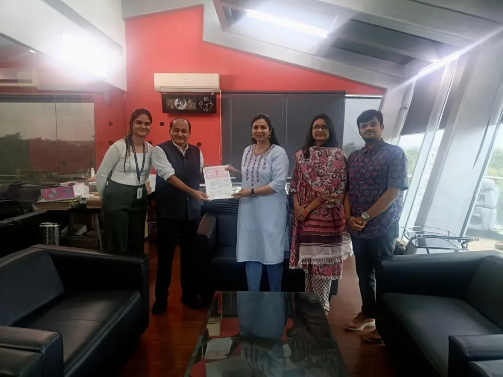 Five people in an office stand together while a signed document is handed over.