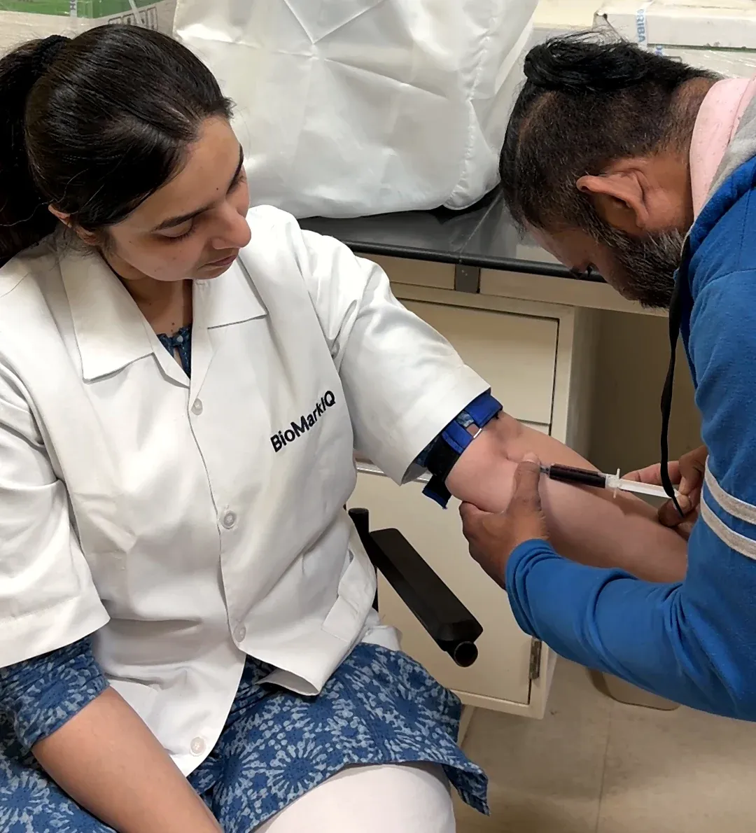 A BioMarkIQ team member in a lab coat gives a blood sample.